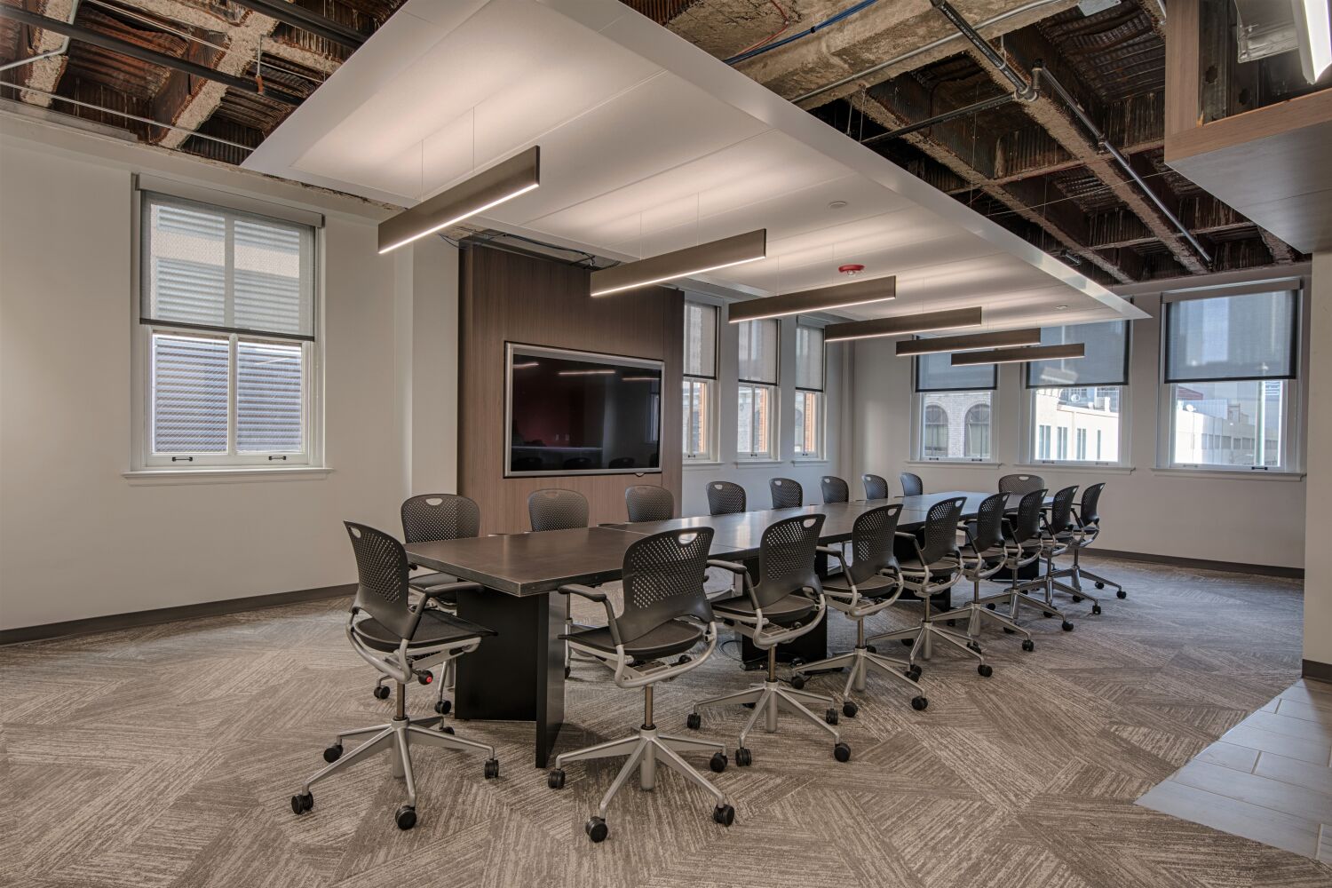 modern conference room with a long table, rolling chairs, and ceiling-mounted lighting
