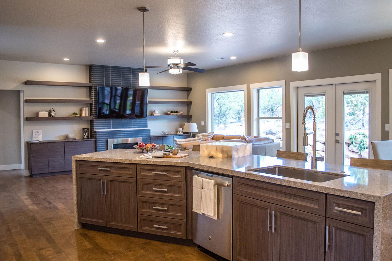 kitchen counter showing brown cabinets, sink, dishwasher, and living room in the background