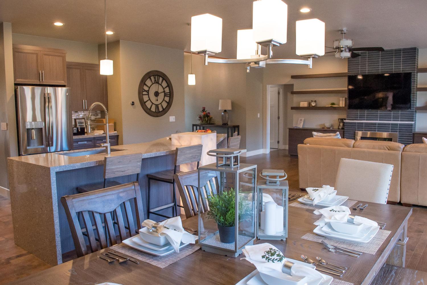 dark brown kitchen table set with white china, white cloth napkins, and silver silverware, with living room in the background of open floor plan 