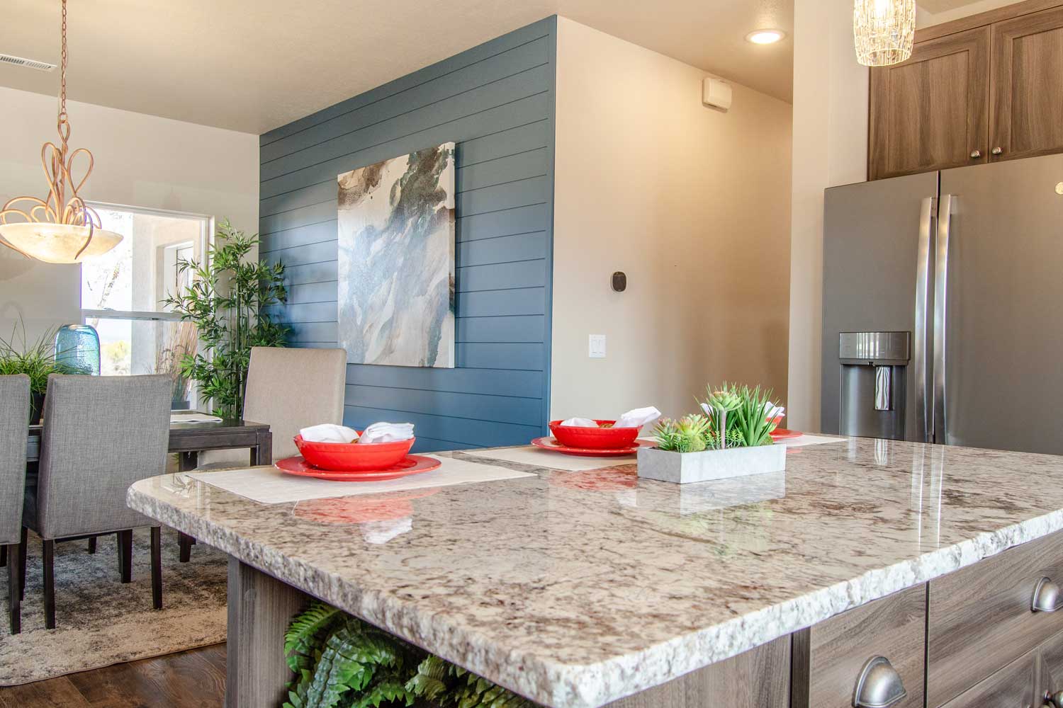 kitchen counter with sitting area and table top set for two with red bowls and white linens