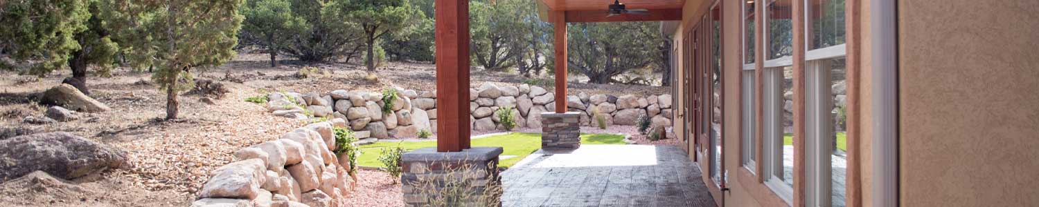 covered patio opening to stone landscaping and wall of windows to the interior