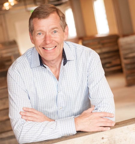 Chris Cipoletti smiling with arms crossed with red brick building in the background