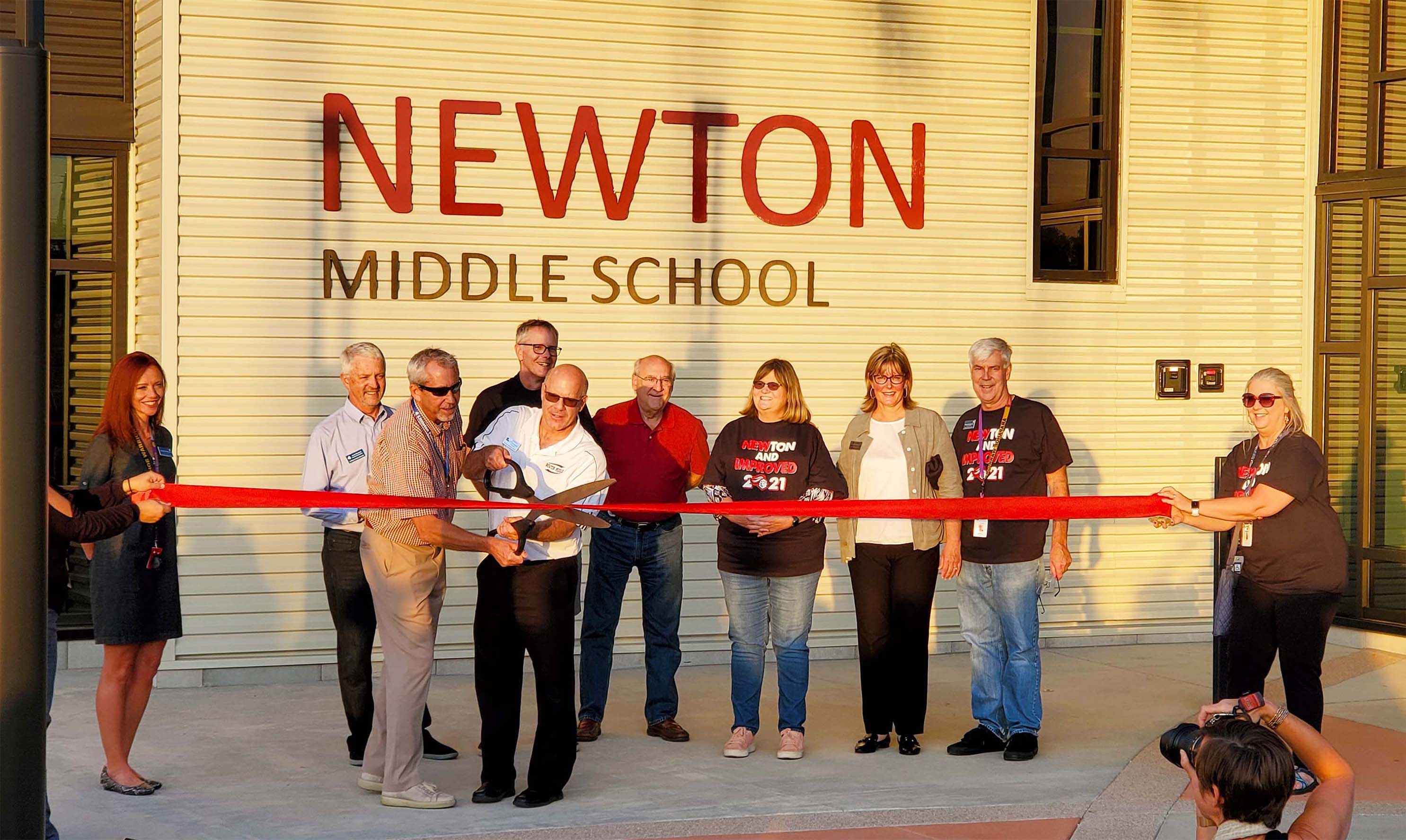 a group of people cut the ribbon for the Newton Middle School Ribbon Cutting ceremony