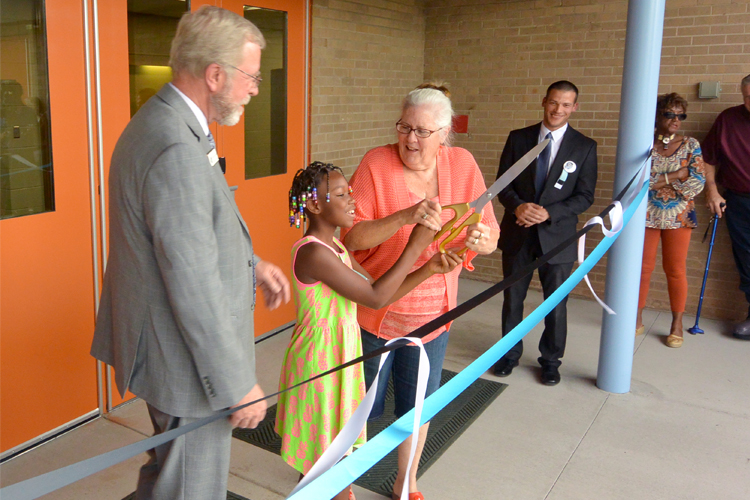 student prepares to cut the ribbon for the renovated adams elementary