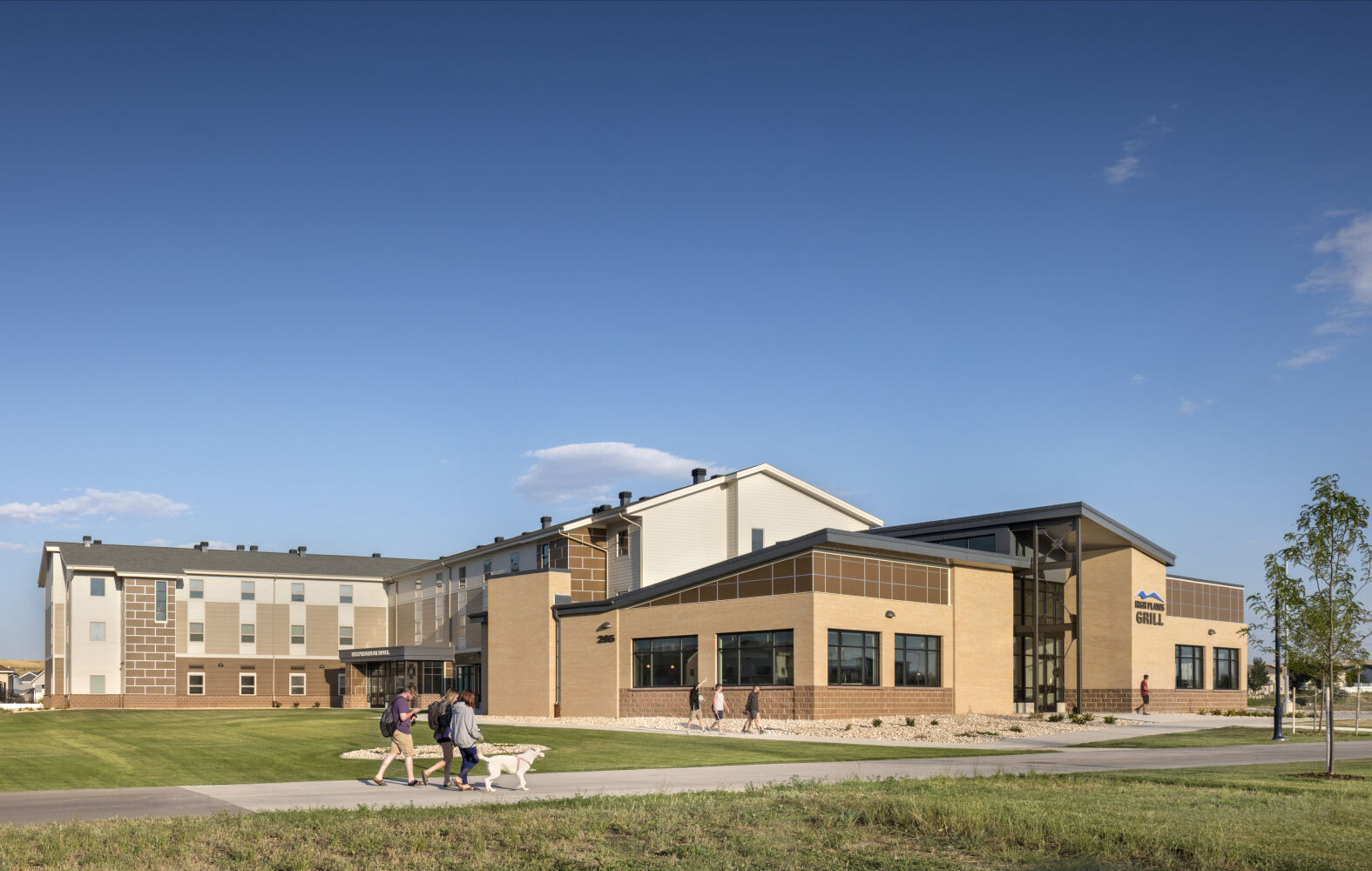 Gillette College Inspiration Hall and High Plains Grill with light‑colored siding, brick accents, and large windows along the campus walkway.