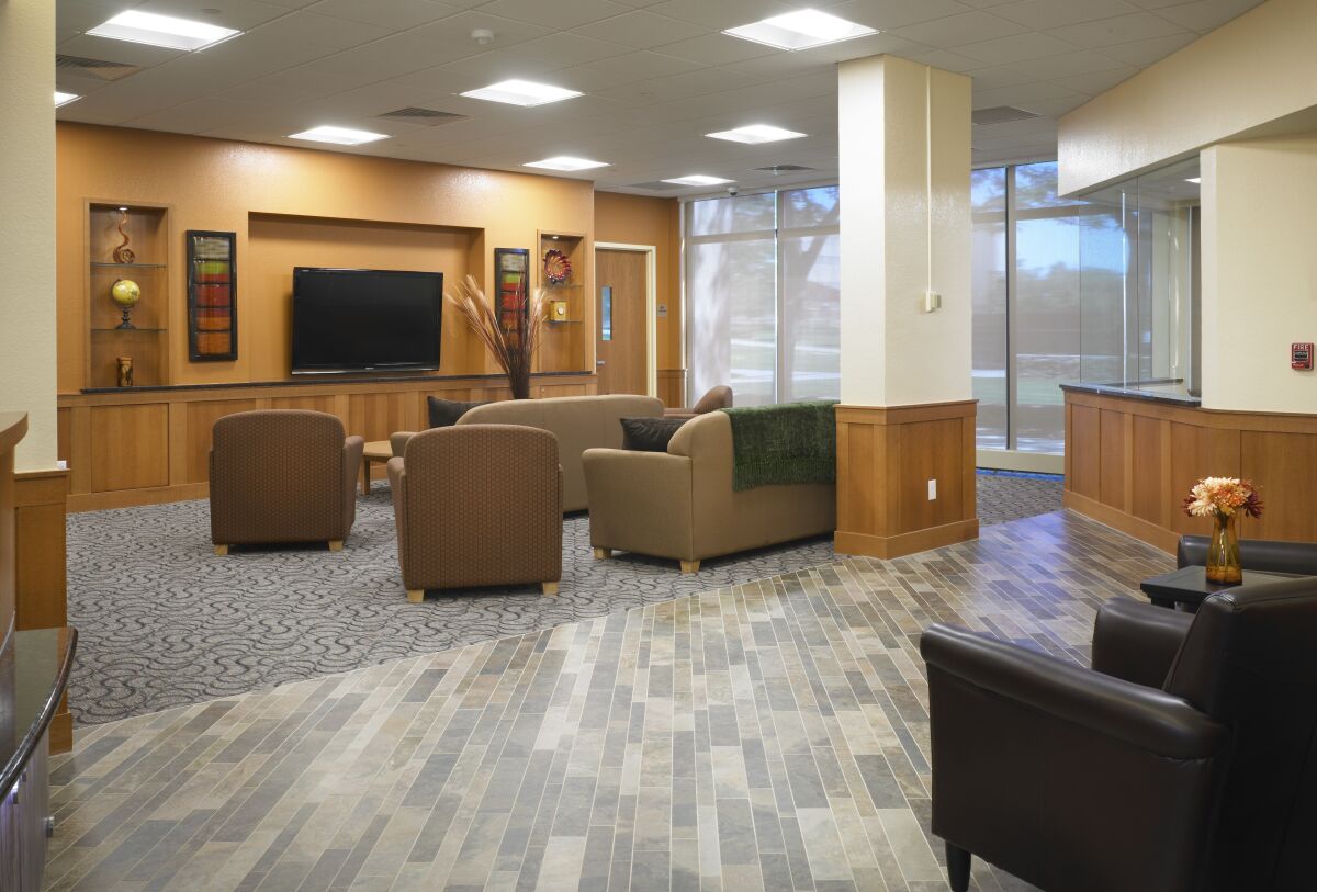 Lobby lounge at University of Northern Colorado Turner Hall with cushioned seating, a wall‑mounted display, built‑in wood casework, and tiled flooring.