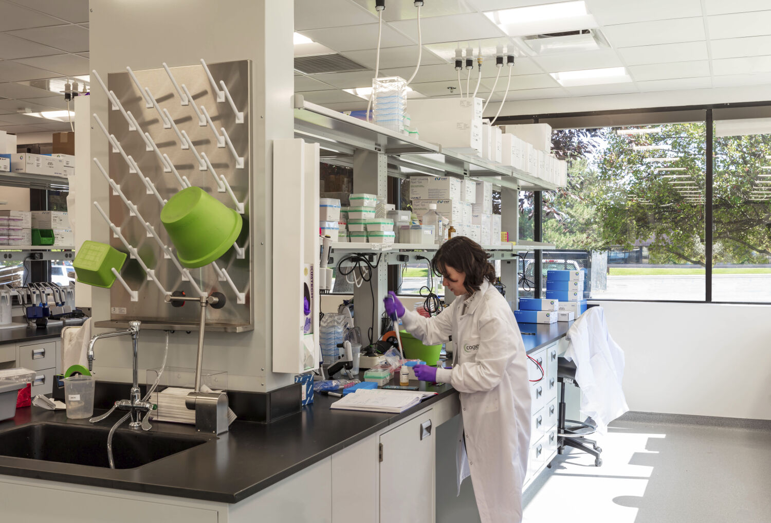 Laboratory at Cogent Biosciences with perimeter work benches, laboratory equipment, overhead shelving, and large windows.