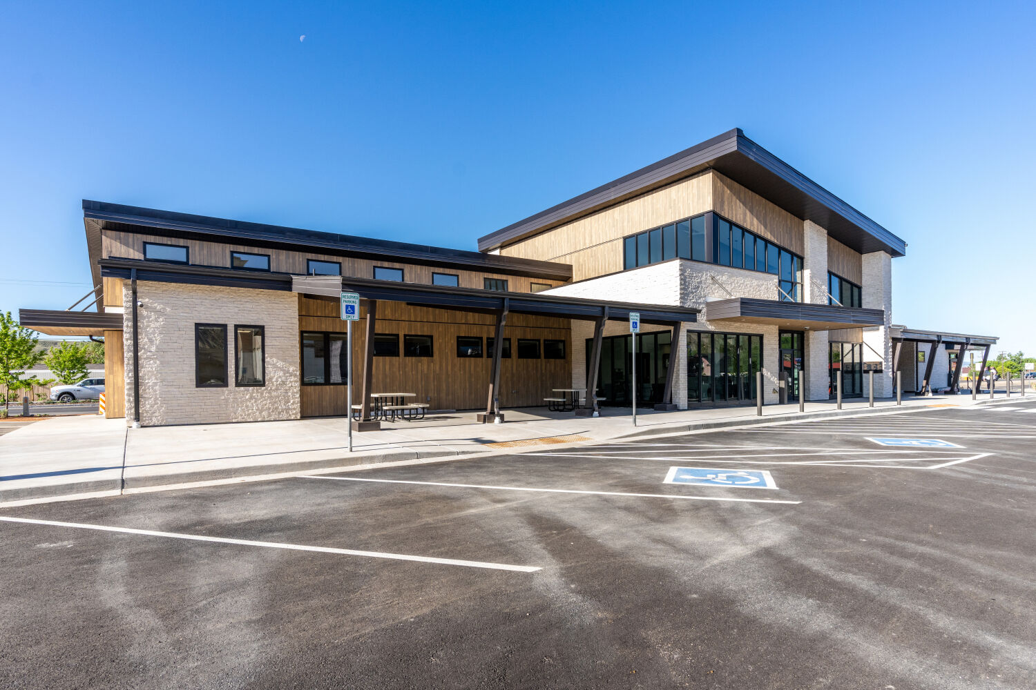 The Grand Valley Primary Care Clinic building with a covered entry canopy, wood and masonry cladding, large glazed windows, accessible parking, and a defined drop‑off approach.