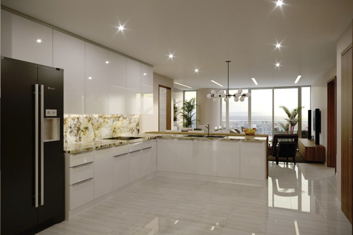 A residential kitchen with glossy cabinetry, integrated appliances, an L‑shaped island with stone countertops, pendant lighting over the dining area, and large windows connecting the kitchen to the adjacent living space.