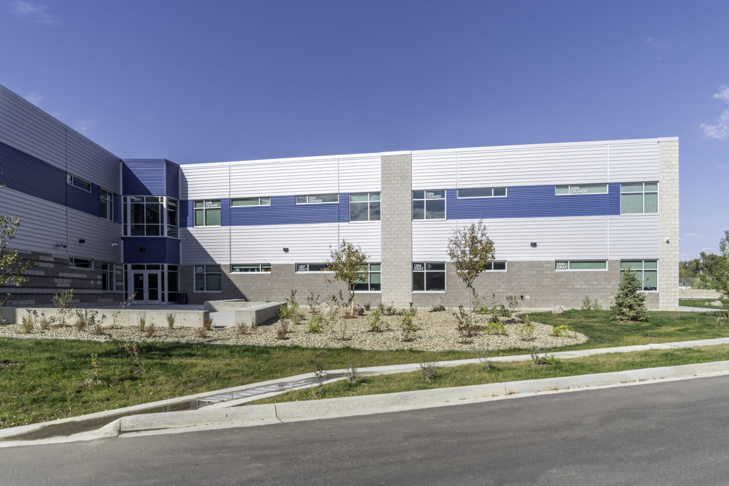 Classroom wing of Nettie S. Freed K–8 Expeditionary School with horizontal metal cladding, brick base, ribbon windows, and landscaped edge along the building.