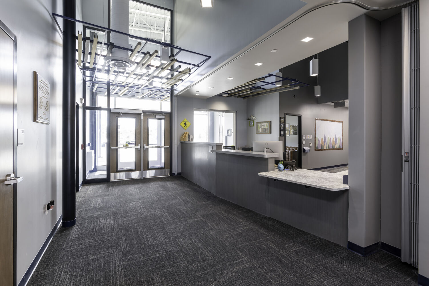 Secure vestibule with controlled entry doors, a reception desk, and acoustic ceiling elements.