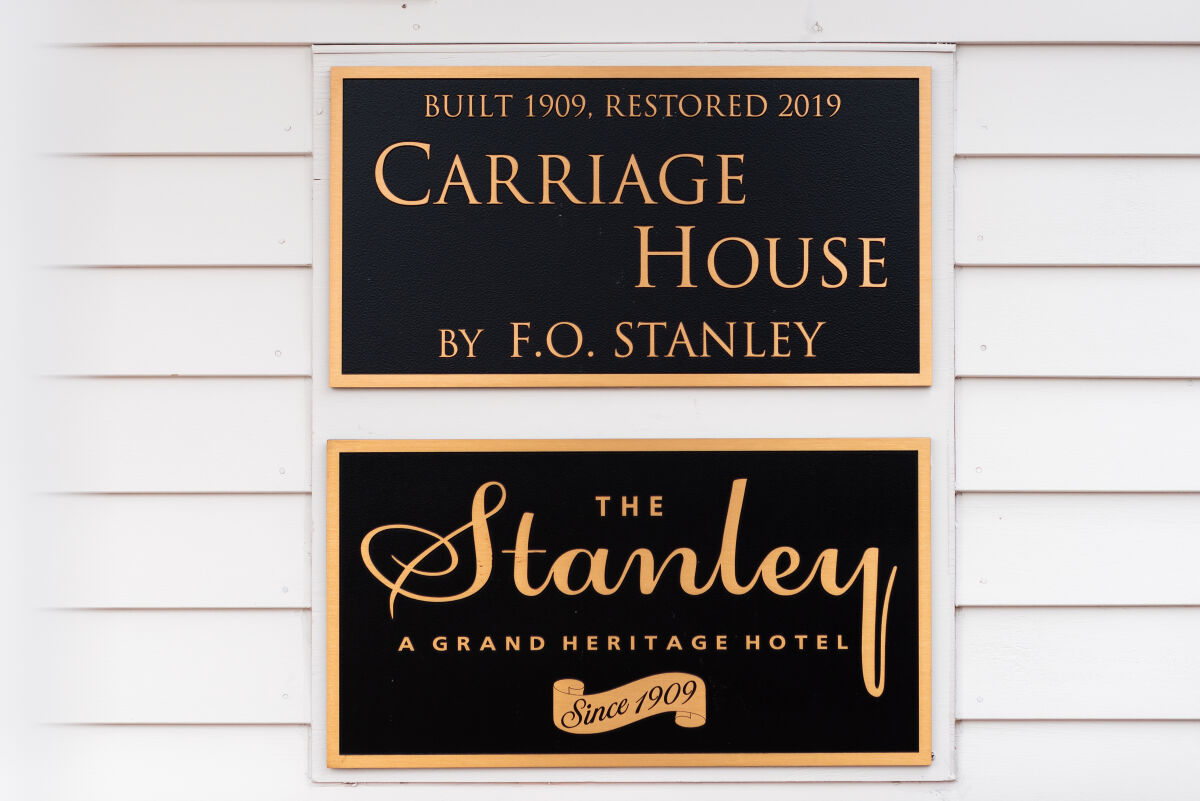 Exterior plaque displaying the historic Carriage House and Stanley Hotel signage mounted on white siding.