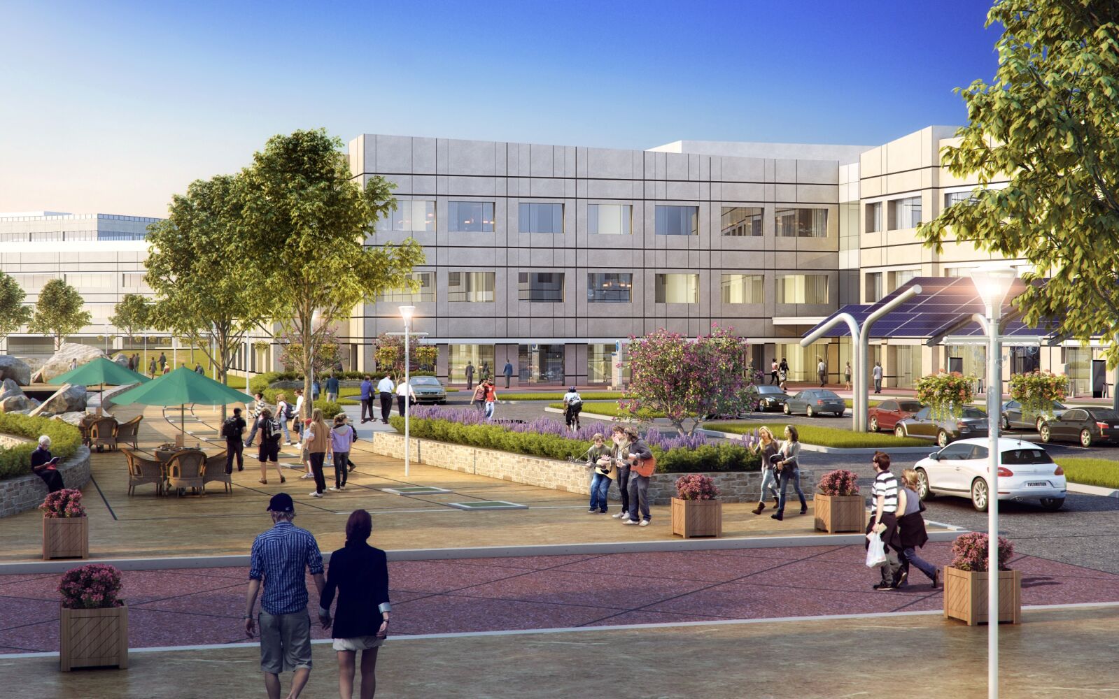 Ground‑level view of a campus plaza with walking paths, outdoor seating areas, landscaping, and a modern office building in the background.