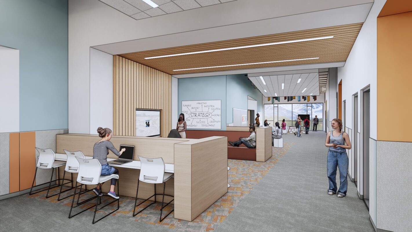 Learning commons with built‑in study stations, lounge seating, wood‑slat ceiling accents, carpet tile flooring, writable wall surfaces, and large windows providing views of the mountains.
