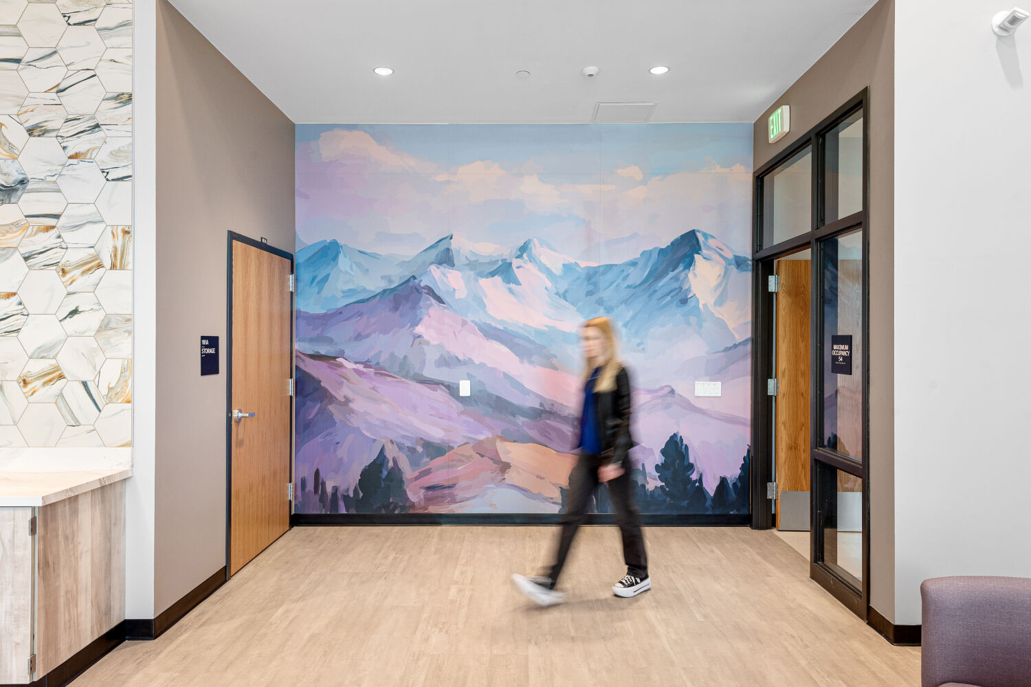 Community room featuring a large mountain landscape mural, resilient flooring, adjacent room entries, and recessed ceiling lighting.