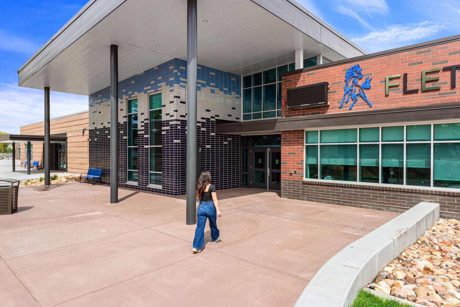 Main entrance of Fletcher Miller School with a covered entry canopy, glazed brick facade, large glazed windows, and a paved entry plaza.
