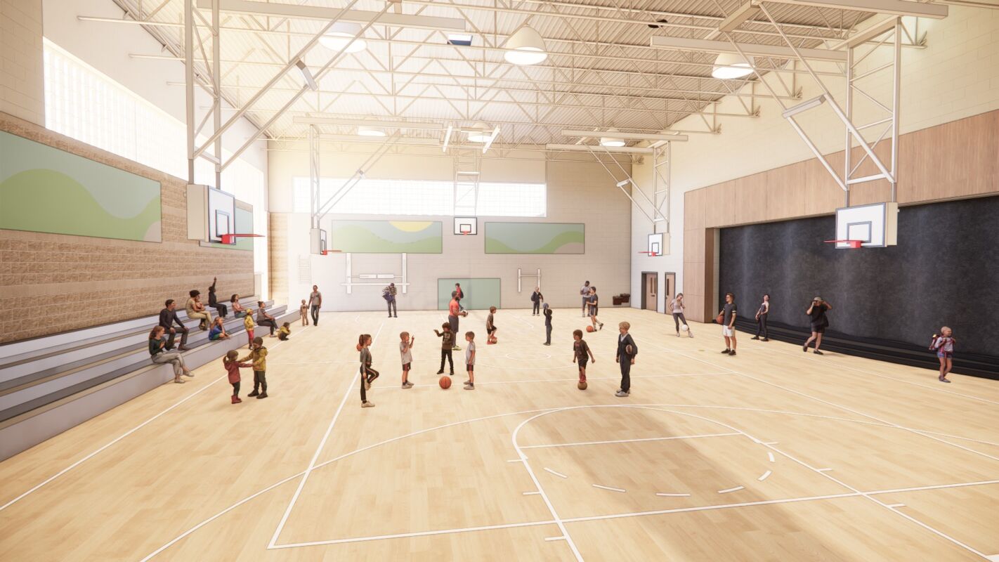 Gymnasium with a wood basketball court, retractable bleachers, multiple backboards, acoustic wall panels, and exposed roof structure with suspended lighting.