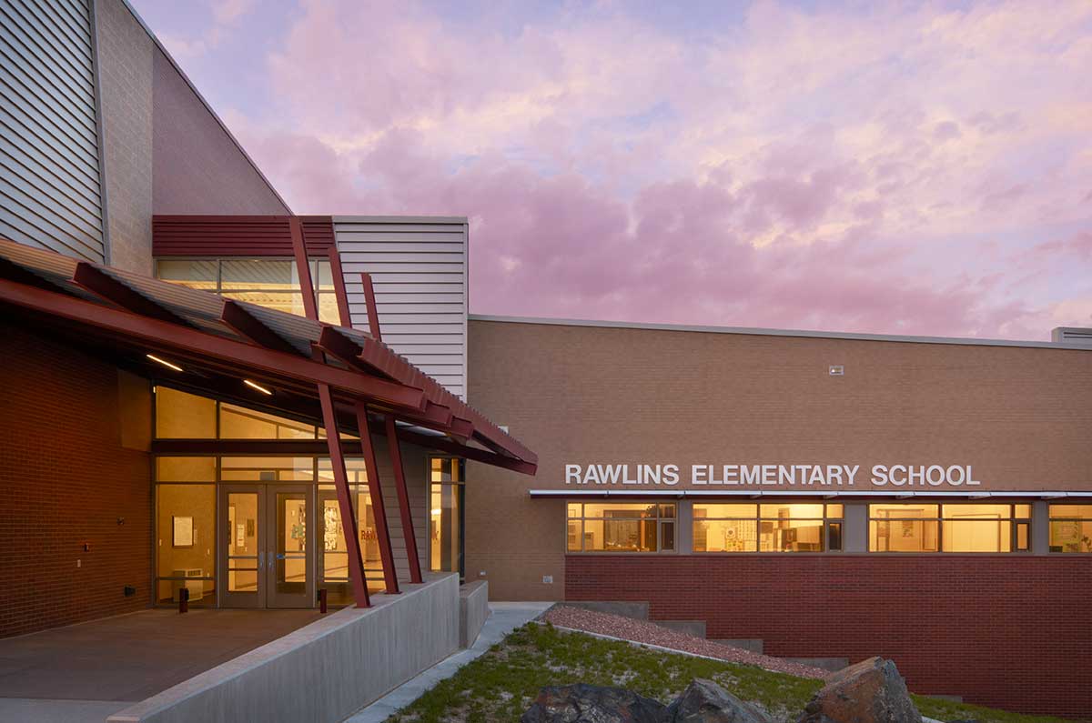 Exterior view of a contemporary educational building with brick and metal siding, large windows, and landscaped walkways in front.