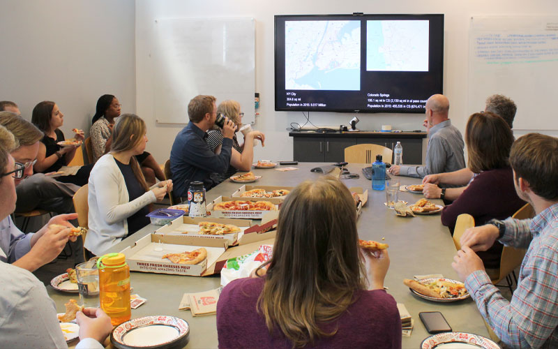 Group of architects sitting around a conference table having lunch and watching a presentation