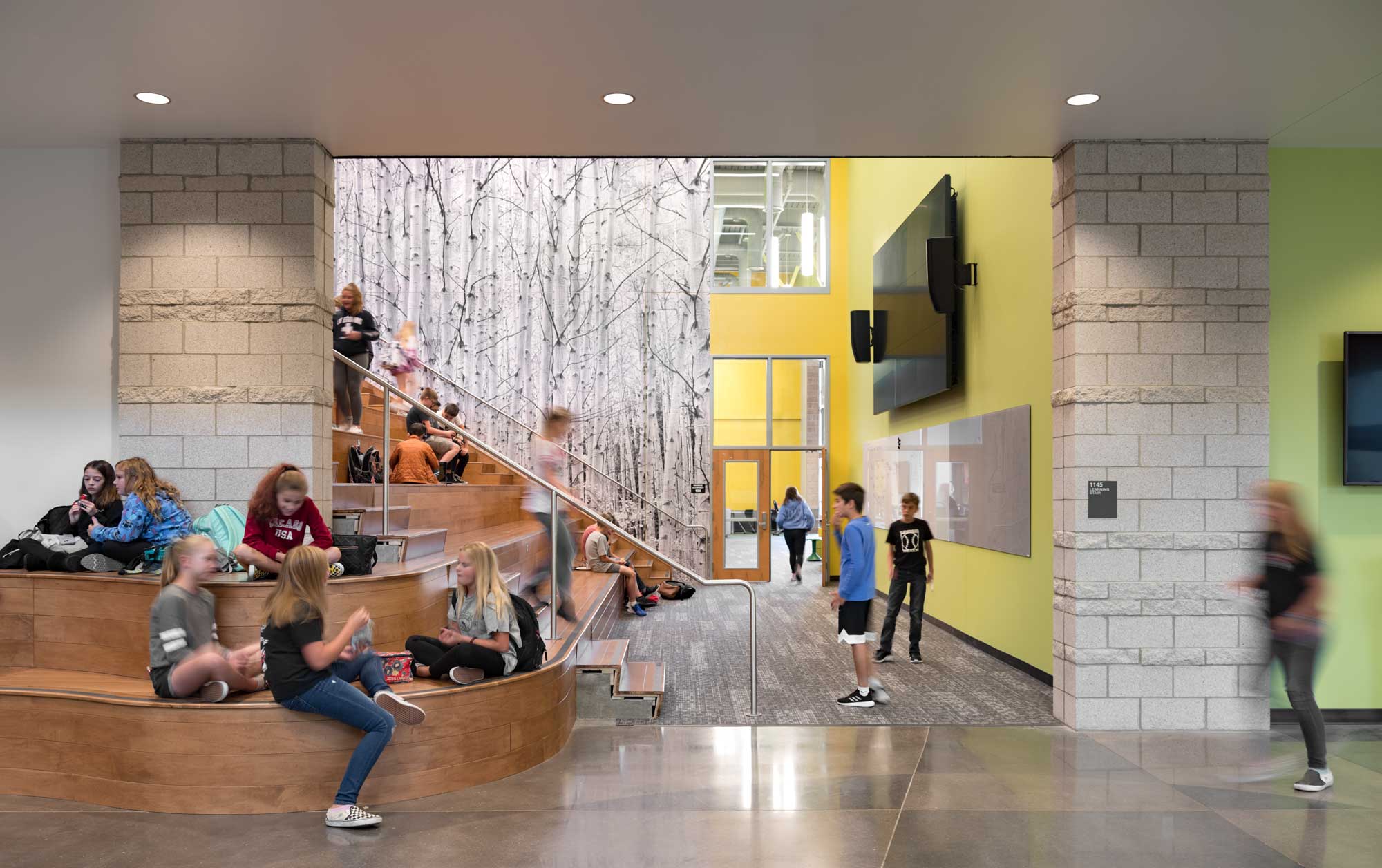 Interior view of a learning stair area at CTMS, featuring wide, tiered seating integrated with wooden steps, modern lighting, and an open layout. The space is designed for collaborative learning and student engagement.