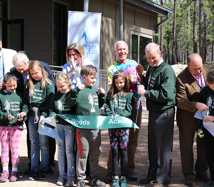 staff and students cut the ribbon for the new school in the woods