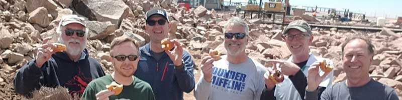 Six people from RTA's leadership team holding up donuts made at the Pikes Peak Summit cafe