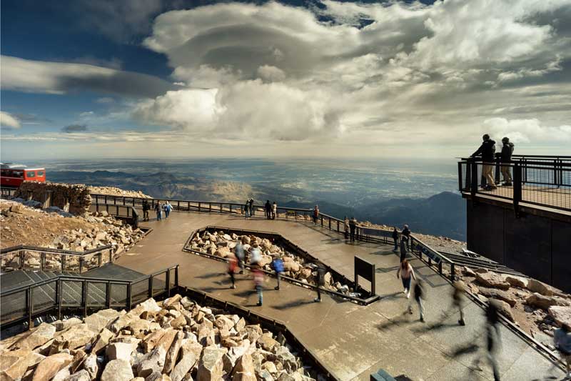 Two people standing at the railing on the deck overlooking the cog railway train