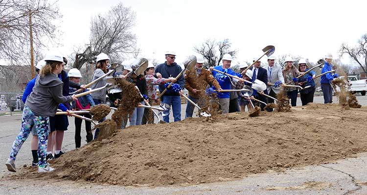 students and staff participating in the ground breaking by shoveling dirt