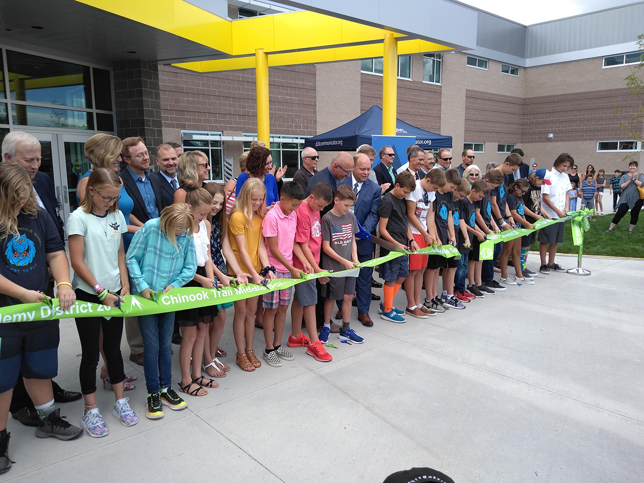 students and staff gather in front of chinook trail middle school to cut the ribbon for the ribbon cutting ceremony