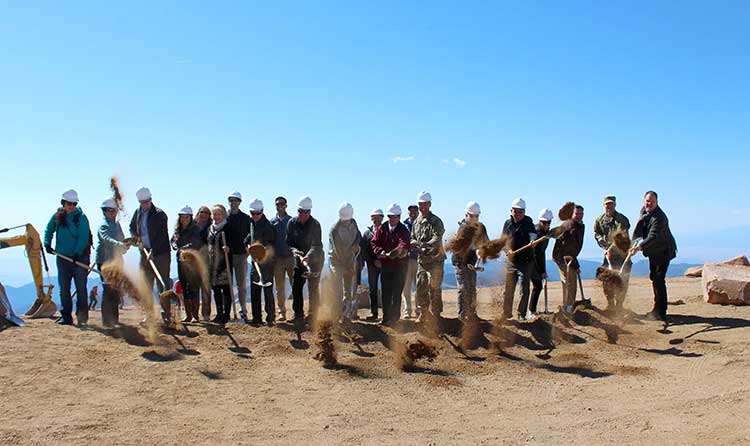 a group shovel dirt atop pikes peak for the groundbreaking of the new visitor center