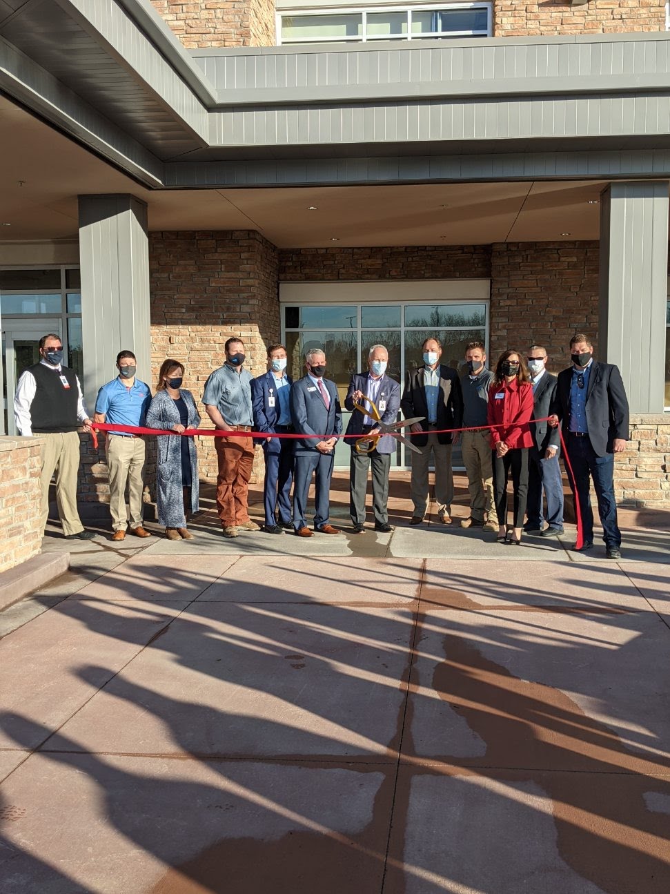 a group prepare to cut the ribbon for the Peak Medical Office Building opening