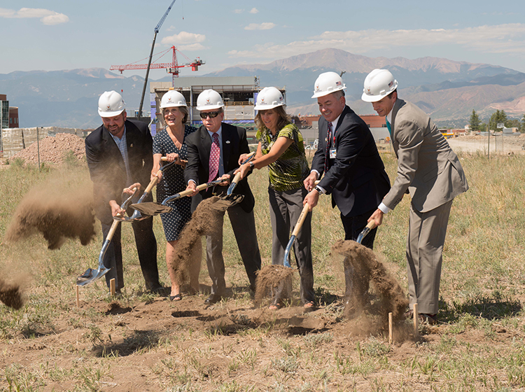 a group of people shovel dirt for the new Ronald McDonald house groundbreaking