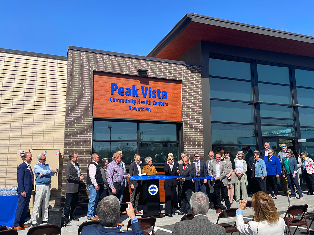 a group stands in front of the new Peak Vista clinic for the ribbon cutting ceremony